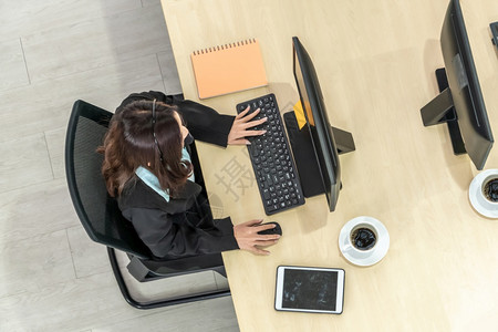办公室内佩戴顶尖头盔的商界人士与计算机合作支持远程客户或同事呼叫中心电话推销代理服务电话或视频会议背景