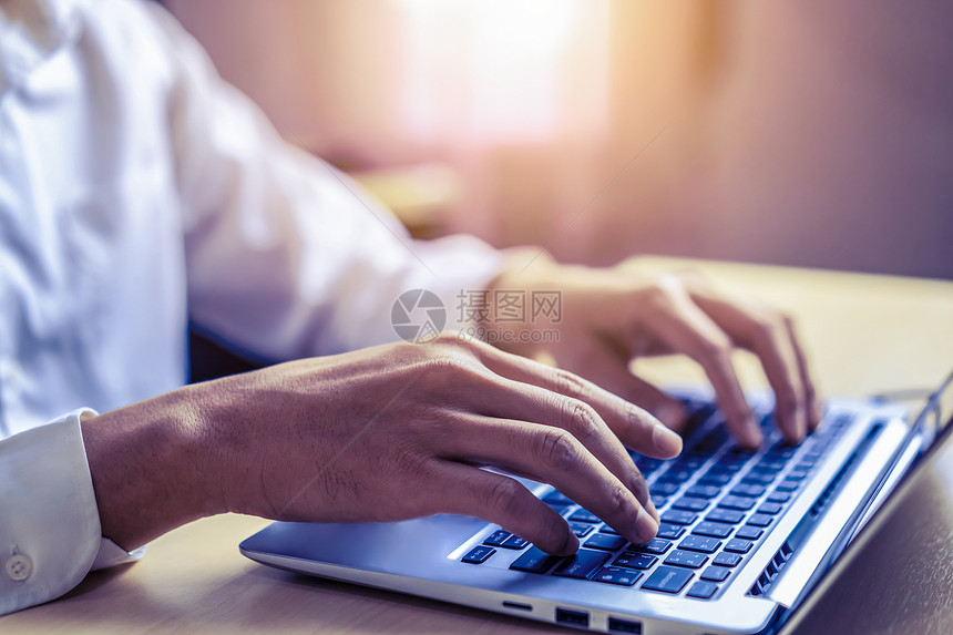商人在办公室一台笔记本电脑的键盘上打手字图片