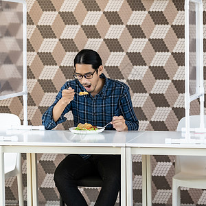 先令Asian青年男子的肖像是在新正常社会距离餐厅吃炒饭桌被挤断厅是新的正常生活方式和食品概念背景