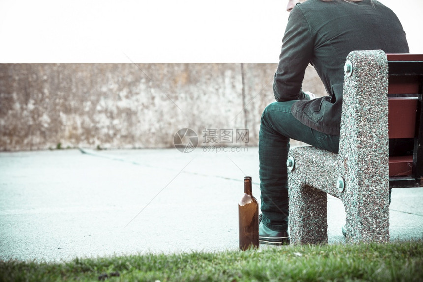 一个人在户外的长椅上喝着酒瓶子一个人在户外的长凳上喝着酒瓶子图片