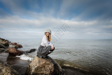 美丽的海边景色概念岩石阴云天的海平面女人看着美丽的风景图片