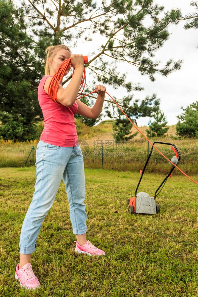 种植后工作的妇女在她手臂上卷起的橙色铁丝电缆除草器设备图片