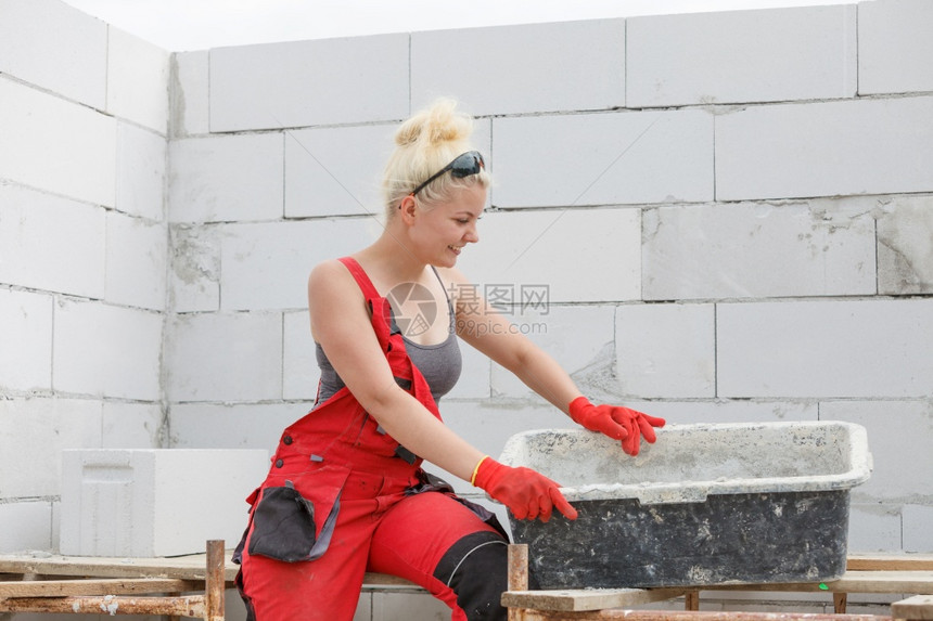 身着便衣的妇女在其住宅建筑工地作在准备迫击的碗里混凝水泥图片