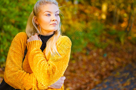 穿着时装黄色羊毛衣在秋天公园行走的妇女图片