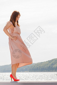 妇女穿着美丽的长短粉红裙子和色高跟鞋穿着长的粉红色裙子图片
