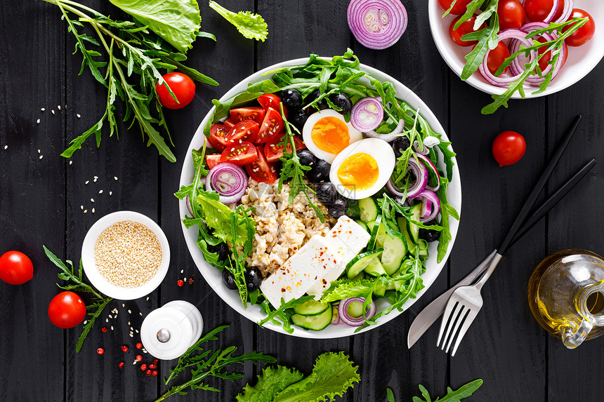 希腊风格的健康早餐碗配有燕麦粥和新鲜蔬菜沙拉包括生黄瓜橄榄番茄奶酪和煮鸡蛋图片