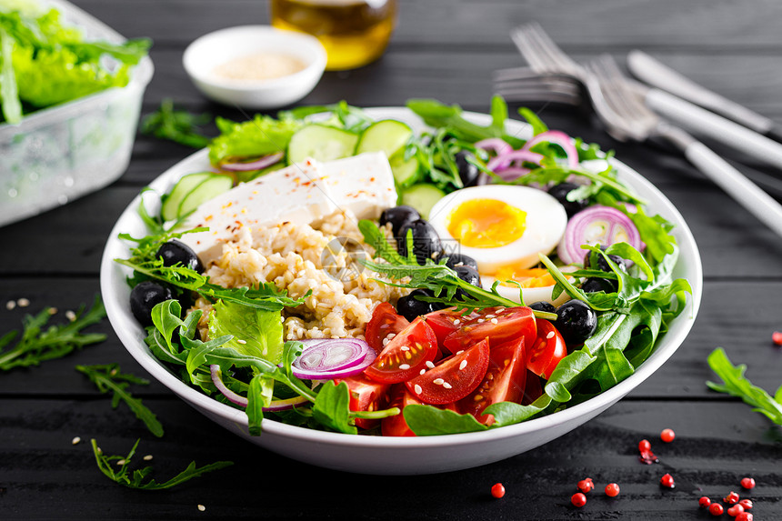 希腊风格的健康早餐碗配有燕麦粥和新鲜蔬菜沙拉包括生黄瓜橄榄番茄奶酪和煮鸡蛋图片