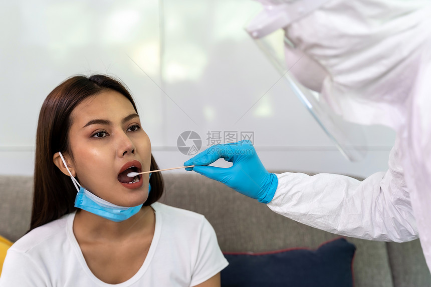 使用个人防护设备服的医务人员在家中用喉咙吸盘对亚洲妇女进行新冠coronaviruscovid19测试在家中提供新的正常保健服务图片
