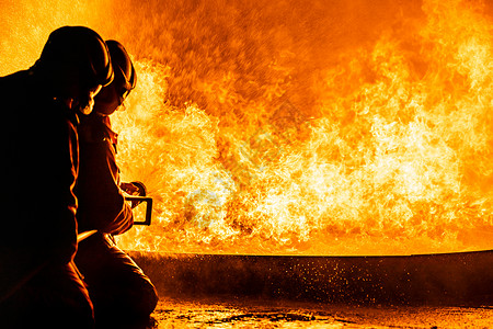 不一样火消防员使用Twirl水雾型灭火器与油的焰抗争以控制火势不扩散消防员和工业安全概念背景