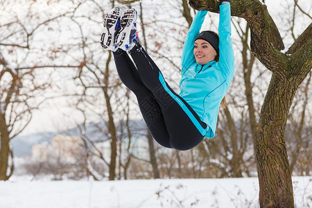 冬季运动户外健身时尚康概念女孩在树上锻炼图片