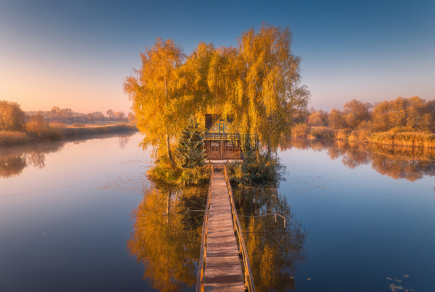 秋天日出时旧渔夫老屋和木码头空中观景湖边小岛上有房子的美丽风景多彩树木码头水面反射在乌克兰坠落顶端观景图片