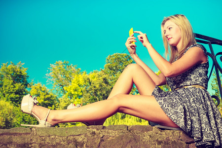 妇女坐在公园休息和使用手机在外闲暇时间妇女坐在公园休息和使用手机图片