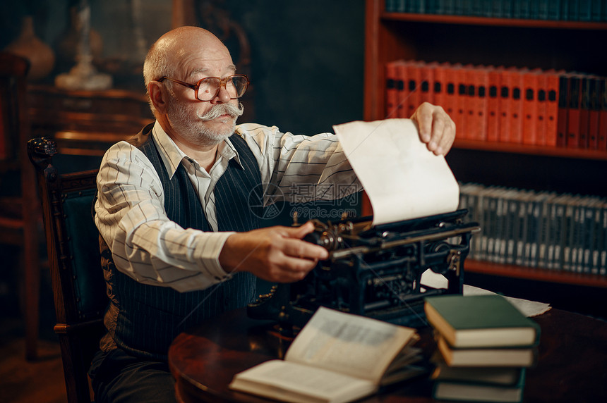 老年人作家将纸张插入其办公室的老式打字机年人在房间里用烟雾写文学小说老年人作家将纸张插入打字机图片