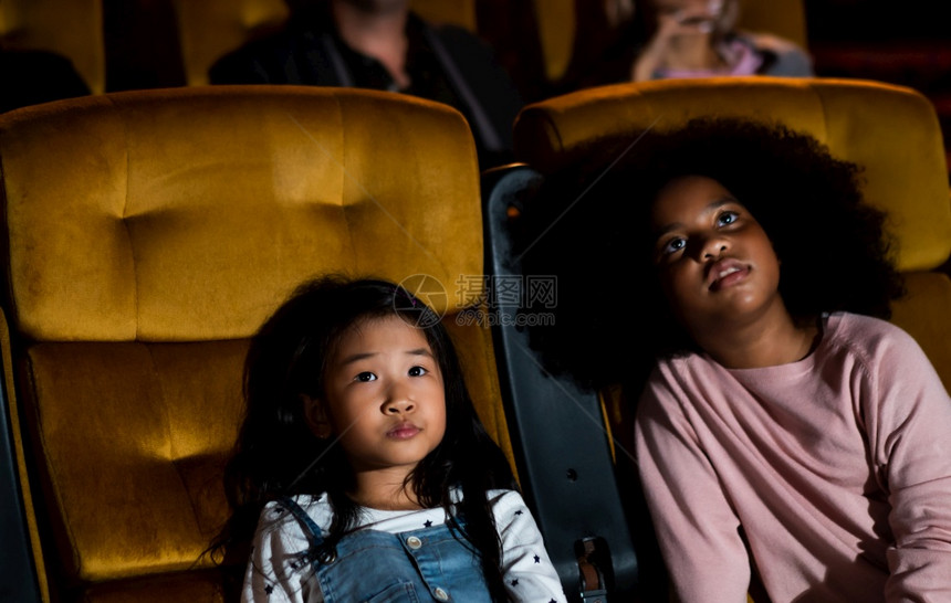 两个非洲和亚裔儿童玩得开心享受在电影中看图片