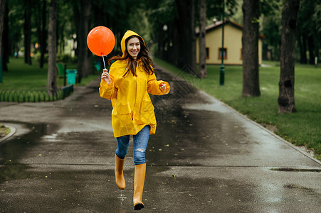 快乐女人在雨天的夏日公园里带着气球跑来去快乐女人在雨天带着气球跑来去图片