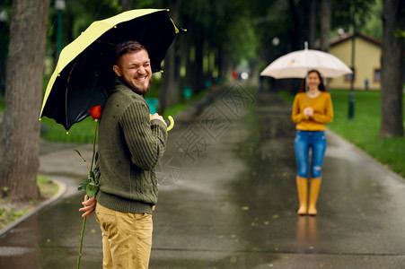 下雨天情侣拿着玫瑰花在公园约会图片