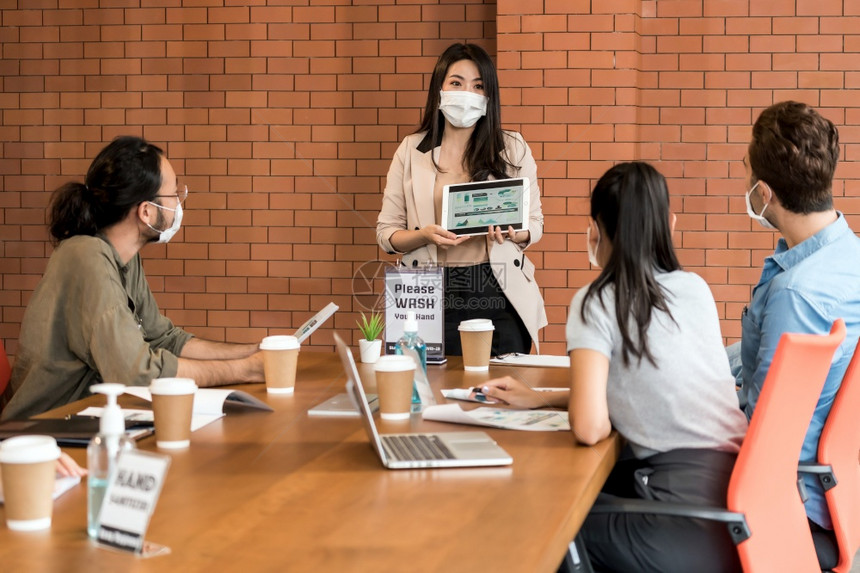 亚洲女商人在集思广益会议上介绍她的工作们在新的正常办公室戴保护面罩防止COVID19冠状扩散图片