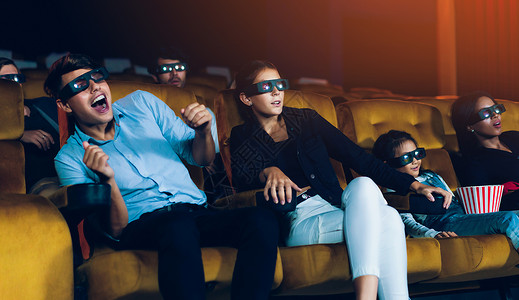 多路复用一群人在电影院看三维眼镜的电影有兴趣观看屏幕奋和吃爆米花背景