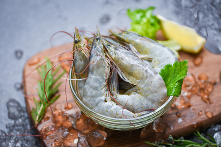 新品上新横板碗上新鲜虾和配有迷迭香成分药草和料的木制切菜板供做饭的海产食品在餐厅冷冻的冰面上生虾背景