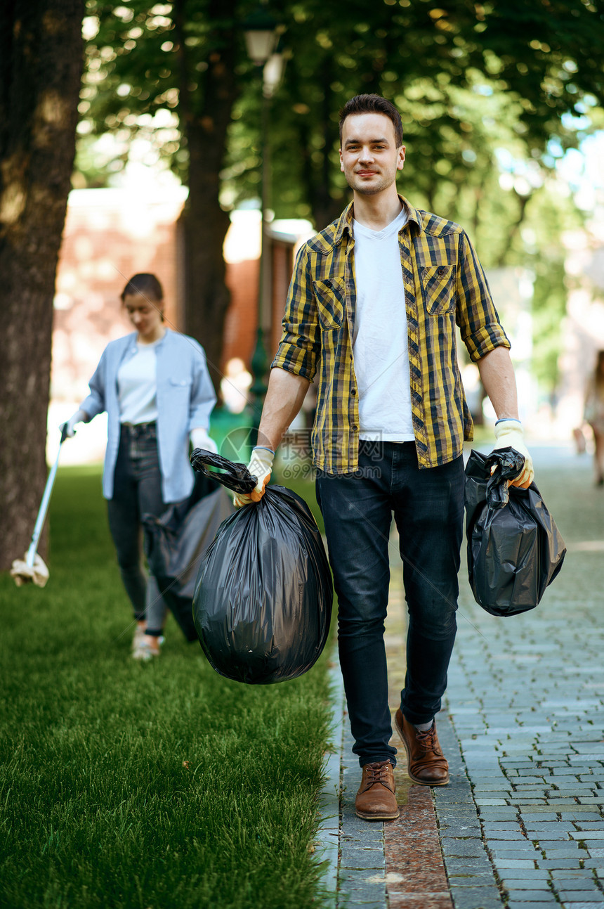 青年男子在公园中持有塑料垃圾袋从事志愿工作男子清洁森林生态恢复活方式垃圾收集和回生态护理环境清洁图片