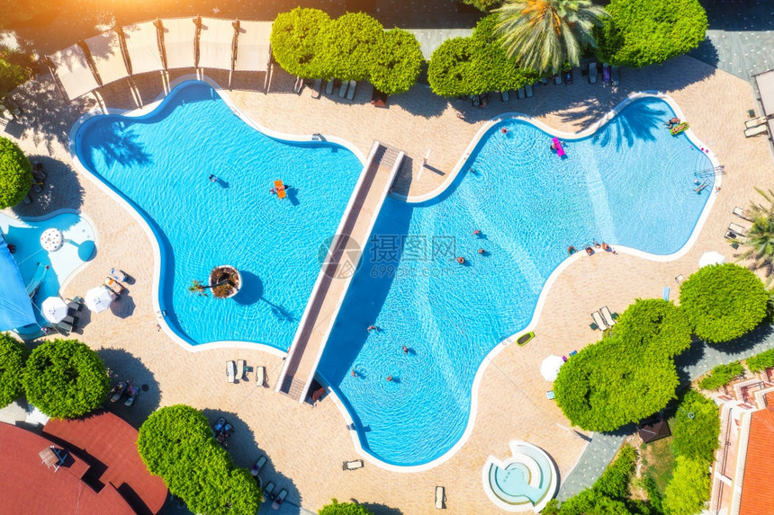 游泳在透明的蓝水中游泳人雨伞遮阳带日落绿树暑假泳池最美景甲板椅欧洲豪华度假胜地的放松和休闲图片