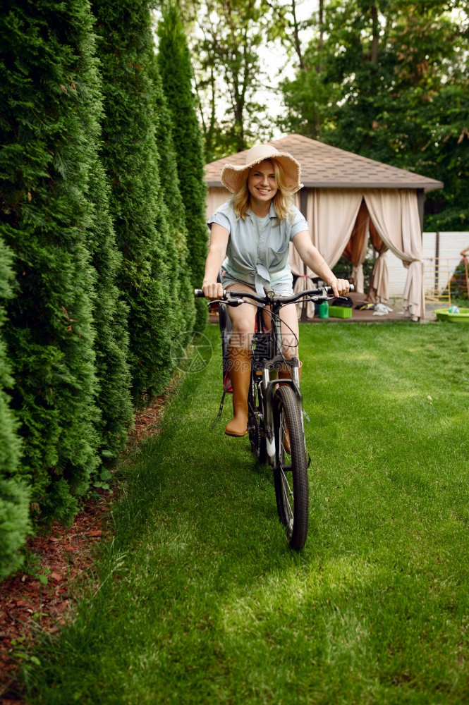 在花园里骑自行车的有吸引力女园丁在花里摆姿势在花园里骑自行车的女园丁在花里摆姿势在户外循环的妇女园艺爱好花卉家生活方式和休闲图片