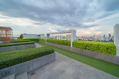 在公用寓或旅馆的私人屋顶上天空花园高楼建筑有树草场和蓝天背景图片