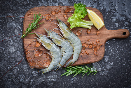 新品上新横板木制切板上新鲜虾配有迷迭香成分药草和料用于烹饪海产食品在餐厅冷冻的冰上生虾背景