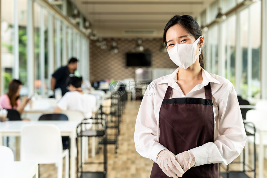 具有吸引力的肖像亚洲女服务员戴面孔顾客背景坐在室内餐厅的社会距离桌子上图片