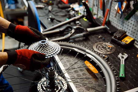 修理车间的自行人安装恒星磁带修理周期有制服问题的机械师专业自行车修理服务车间的自行修理人安装磁带背景图片