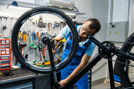 修理车间的自行修理男子设置刹车穿制服修理自行车的机械师专业自行车修理服务间的自行修理背景