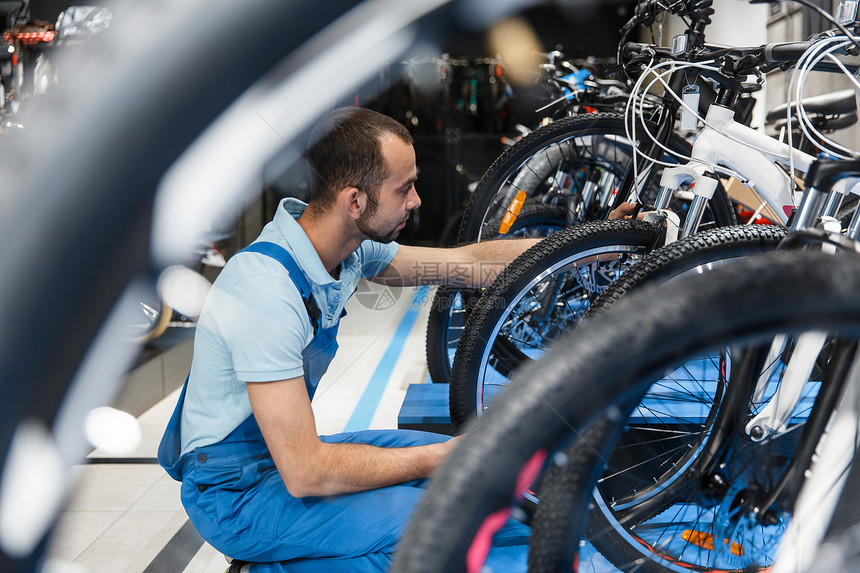 自行车店修理工看新自行车穿制服的机械师修车专业理和销售服务图片