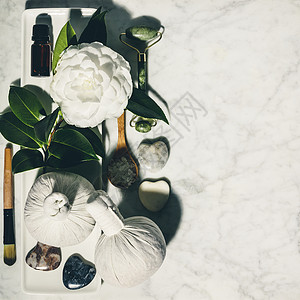 与春花和各种美容产品玉滚花海盐草药按摩球基本油白大理石桌上的块图片