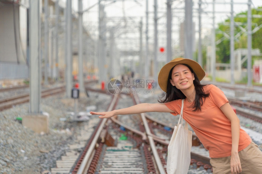 亚洲妇女是旅游者乘火车或电在铁路上旅行城市终点站乘坐电线杆塔和缆乘坐公共交通图片