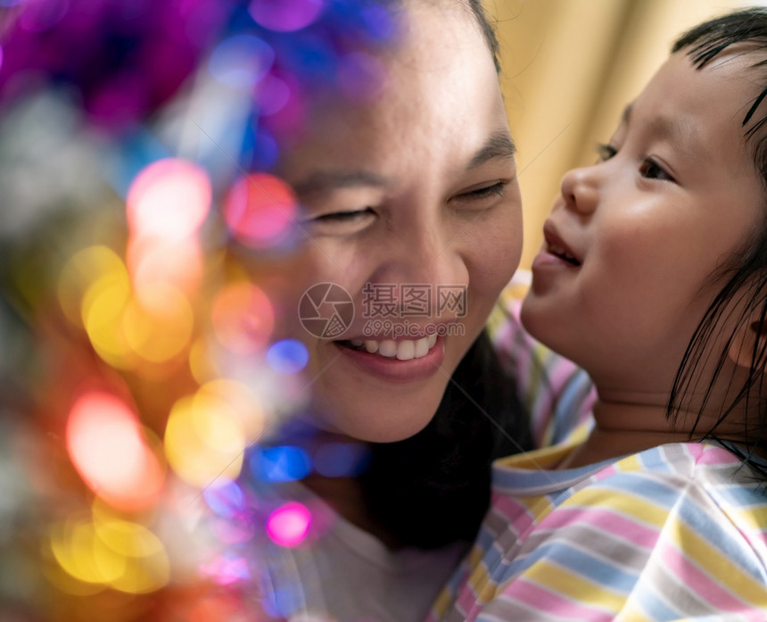 有妈在客厅装饰圣诞树的亚洲小女孩带着圣诞装饰品准备一起迎接季节的问候多代家庭参与和幸福概念图片