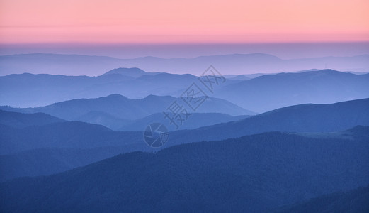 秋天日落时雾中山脊美丽的风景有雾山谷岩石森林红天在黄昏时蓝色钟坠落山的空中景象顶端风自然背背景图片