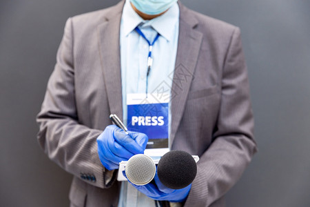 造谣记者在新闻发布会或媒体活动记者上佩戴防护手套和面罩防止冠状新冠19疾病背景