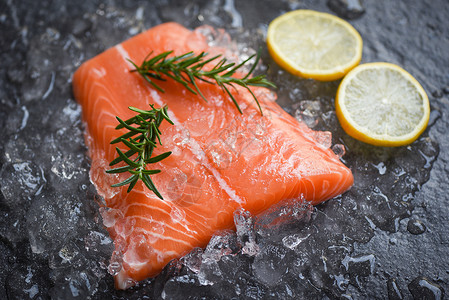 冰上新鲜生鲑鱼牛排有迷迭香食品柠檬和深岩背景图片