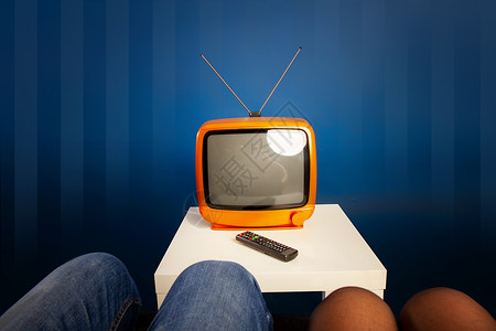 一对已婚夫妇在小台旧电视机前和遥控器一起打开图片