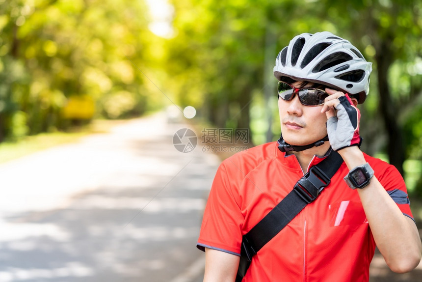 穿着运动服的亚洲男骑自行车运动员的肖像他自行车在农村公路上背景是绿树周末户外运动员和健身概念图片