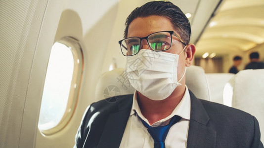 旅行者戴着口罩乘坐商业飞机旅行图片