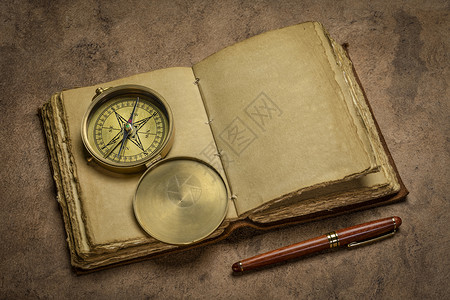 古老的皮质订金日记在古老的木制桌子上印有甲板边缘手工纸页并配有时髦的钢笔和老旧黄铜罗盘日记概念背景图片