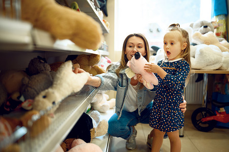 母亲和可爱的女儿在玩具店快乐的童年家庭在商店购买妈和小女孩选择了软玩具孩子和女儿选择了软玩具孩子和女儿商店妈和小女孩选择了软玩具背景图片