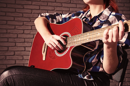 穿着格子衬衫的年轻女孩玩木制古典吉他特写图片