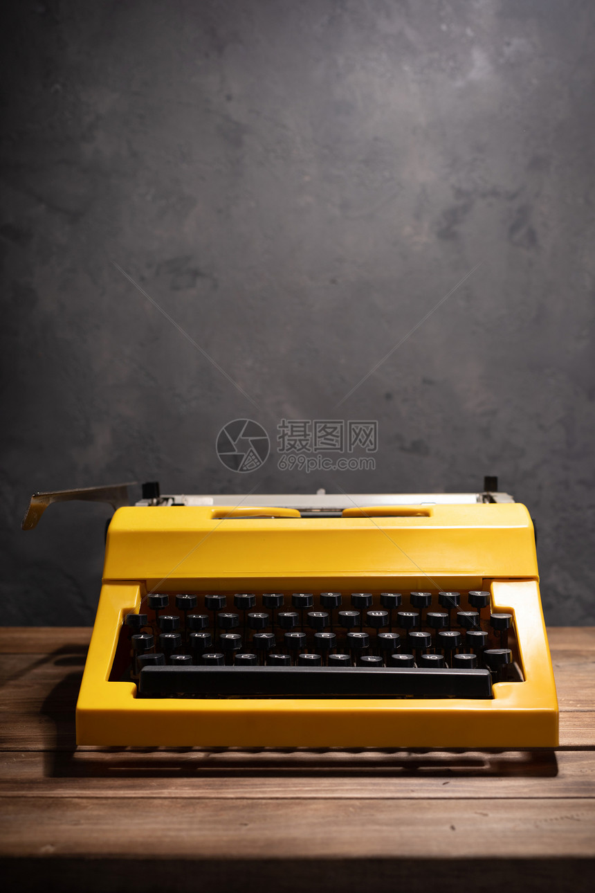 靠近墙背景表面编剧或复写概念的木制顶台黄色老式打字机图片