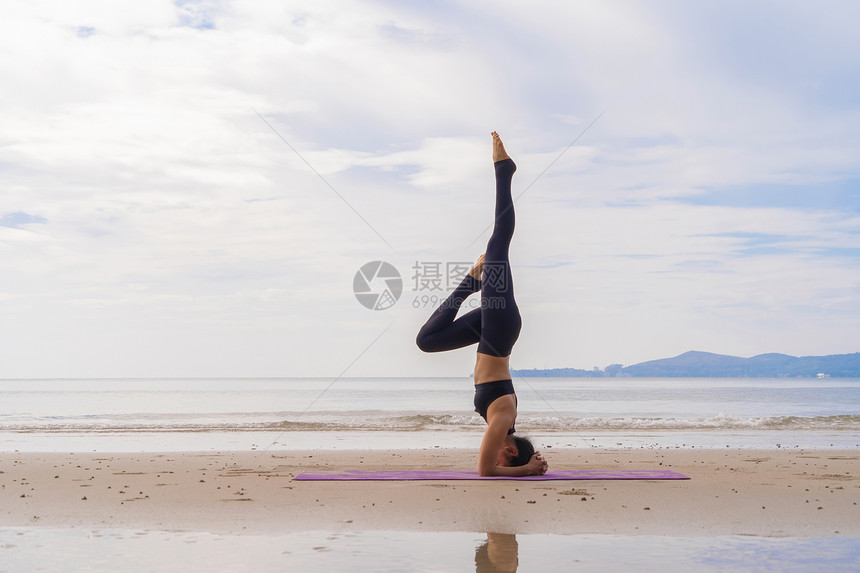 一名在瑜伽班俱乐部的亚洲妇女在自然海滩和滨户外从事运动和娱乐概念方面的锻炼和瑜伽图片