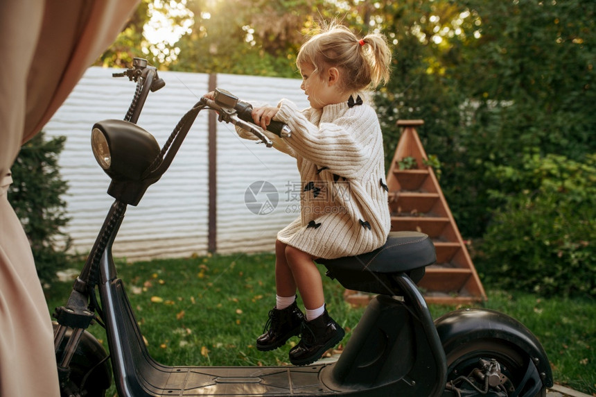女孩坐在花园的老式摩托车上图片