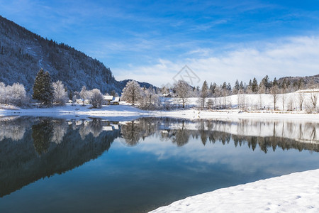 古老的冬季风景反思湖房屋雪树和山岳图片