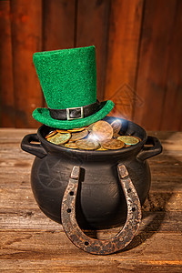 一顶帽子黑锅里的宝藏和一顶绿色小妖精帽子在木制桌上背景