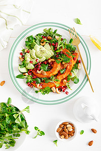 新鲜蔬菜沙拉配有羊肉生菜烤胡桃南瓜或鳄梨石榴腰果和杏仁健康素食品概念图片